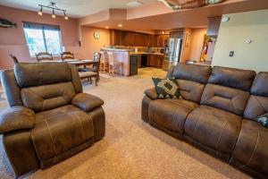 a living room with two leather couches and a kitchen at Bear Creek Lodge - Spa - Fire Table - 3min to Trails in Colorado Springs