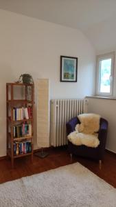 ein Wohnzimmer mit einem Stuhl und einem Bücherregal in der Unterkunft FeWo im Naturschutzgebiet in Hiddenhausen