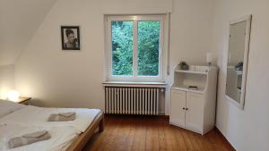 a white bedroom with a bed and a window at FeWo im Naturschutzgebiet in Hiddenhausen