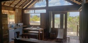 - une cuisine avec une table et des chaises dans une chambre dotée de fenêtres dans l'établissement Divino Tatajuba bungalows, Vista para o mar!, à Tatajuba