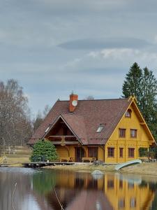 a large yellow house with a pond in front of it at Jaun-Ieviņas in Rauna