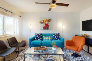 uma sala de estar com um sofá azul e cadeiras laranja em South River Condo em Austin