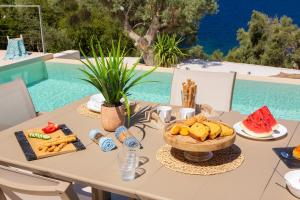 a table with a bowl of bread and a bowl of fruit at Villa Mironi - Private sea access in Marantochori