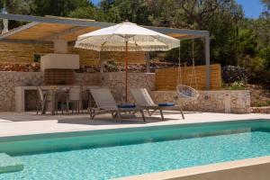 a patio with a table and an umbrella next to a pool at Villa Mironi - Private sea access in Marantochori