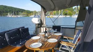 uma mesa de madeira num barco com pratos e copos de vinho em Vedette Hollandaise de 13 m pour séjour insolite em Nivillac