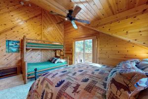 Dormitorio en cabaña de madera con cama y ventilador de techo en Branchwater Lodge, en Big Bear Lake