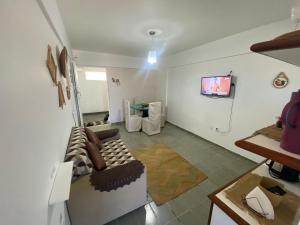 uma sala de estar com um sofá e uma televisão na parede em Confortável Apto com Manobrista Wi-fi - Tv Smart - piscina - Apto 703 em Maceió