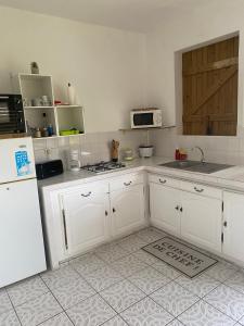a kitchen with white cabinets and a white refrigerator at Au Gré des Alizés - Kaz Soley Péyi in Capesterre-de-Marie-Galante