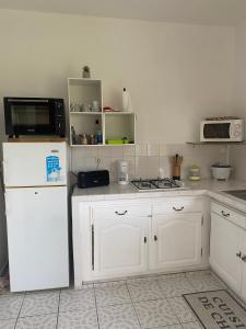 a kitchen with white cabinets and a white refrigerator at Au Gré des Alizés - Kaz Soley Péyi in Capesterre-de-Marie-Galante