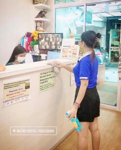 una mujer está parada en un mostrador en una tienda en Micro Hostel, en Bangkok