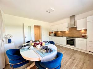 a kitchen and dining room with a table and blue chairs at SEE-Residenz ST. ANNA - mit exklusivem Seezugang in Maria Wörth