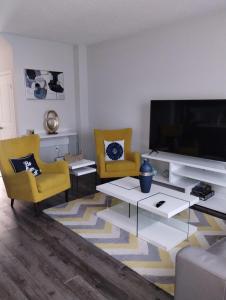 a living room with a large television and yellow chairs at luxurious 3-bedroom residential home in Lincoln in Beamsville