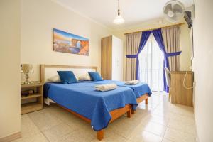 a bedroom with two beds with blue sheets and a window at Lantern Guest House in Marsalforn