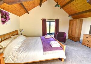 a bedroom with a large bed with a purple blanket at Y Beudy in Llandinam