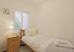 a bedroom with a bed and a dresser and a window at Bailey Cottage in Orford