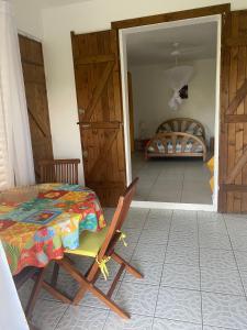 una camera con tavolo e sedia e una camera da letto di Au Gré des Alizés - Kaz Soley Péyi a Capesterre
