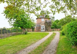 a brick house in the middle of a field with a dirt road at Sampson's Mill in Wickham Market