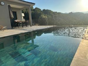 - une piscine avec une table et des chaises à côté d'une maison dans l'établissement A CASA DI LAURENA piscine chauffée proche St Florent, à Vallecalle