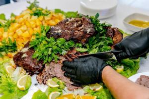een persoon in zwarte handschoenen die een bord voedsel bereidt bij Agriturismo Sabidor in Malalbergo
