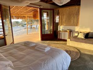 a bedroom with a bed and a view of a patio at LA DUNE DES SONGES in Anakao
