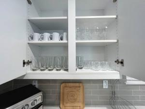 een keuken met witte kasten met glazen op de planken bij Modern Lux Home Near Disneyland And In The Heart Of OC! in Santa Ana