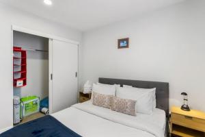 a bedroom with a large bed with white sheets and pillows at Quality in Heart of Albany - Wi-Fi - Free Parking in Auckland