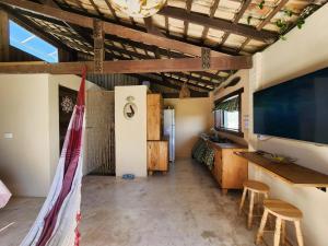 a living room with a large screen tv and stools at Loft romântico pé na areia in Itapoa