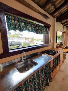 uma cozinha com um lavatório e uma janela em Loft romântico pé na areia em Itapoá