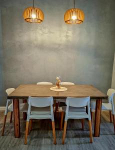 a dining room table with white chairs and two lights at Lechuza Alvear in San Antonio de Areco
