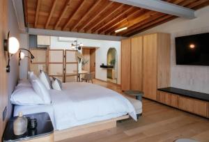 a bedroom with a large white bed and a flat screen tv at Colima 71 Art - Community - Hotel in Mexico City
