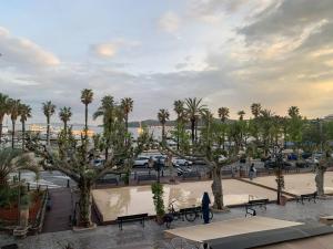 einen Park mit Bänken und Palmen und einen Parkplatz in der Unterkunft T3 vue mer in Le Lavandou