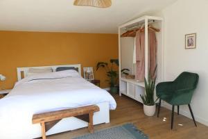 ein Schlafzimmer mit einem weißen Bett und einem grünen Stuhl in der Unterkunft La villa Mama (65 m2), avec piscine partagée in Erquy