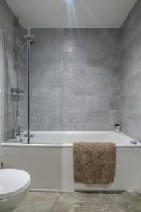 a bathroom with a white tub and a toilet at Modern and Spacious Apartment in Salford Quays in Manchester