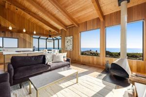 a living room with a couch and a kitchen with windows at Breakers Retreat in Sea Ranch