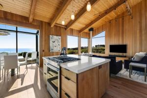 a kitchen and living room with wood walls and windows at Breakers Retreat in Sea Ranch