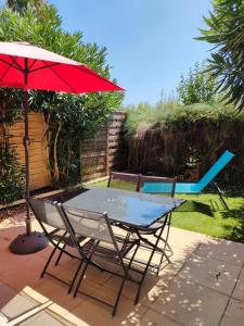 una mesa, sillas y una sombrilla en el patio en appartement en rez-de-chaussée et terrasse sans vis a vis en Canet-en-Roussillon
