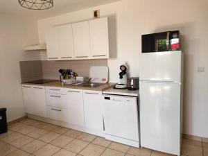 a kitchen with white cabinets and a white refrigerator at appartement en rez-de-chaussée et terrasse sans vis a vis in Canet-en-Roussillon