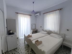 a white bedroom with two beds and a television at Maria Pantermou Rooms in Skala Eresou