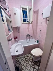 a pink bathroom with a toilet and a tub and a sink at Apartments / Studio Matka in Matka +19 photos