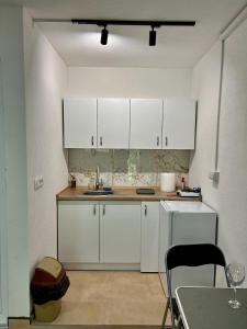 - une cuisine avec des placards blancs, une table et des chaises dans l'établissement Apartments / Studio Matka, à Matka