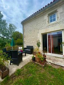 une terrasse avec mobilier et plantes en pot en face d'une maison dans l'établissement la maison d'hôtes des Charentes, à Les Touches-de-Périgny