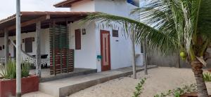 a white house with a red door and a palm tree at Casa do Kite in Galinhos