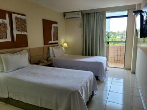 una camera d'albergo con due letti e un balcone di Praiabella Hotel a São Luís