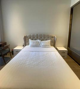 um quarto com uma grande cama branca com lençóis brancos em Losso Wynn em Ho Chi Minh