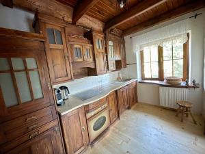 a kitchen with wooden cabinets and a sink and a window at Domek na Cuplu - opcjonalnie balia jacuzzi in Szczyrk