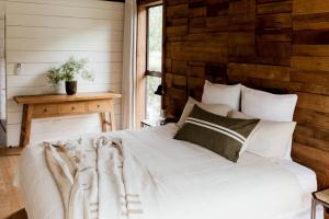 a bedroom with a white bed with a wooden wall at The Villa at Bali Garden Matakana in Omaha
