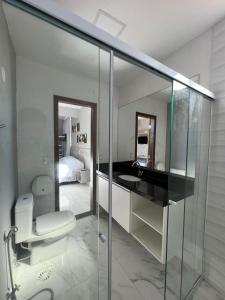 a bathroom with a toilet and a sink and a mirror at Enseada Beach Hotel in Guarujá