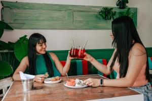 two women sitting at a table with drinks at Cordova Hostel Medellin in Medellín