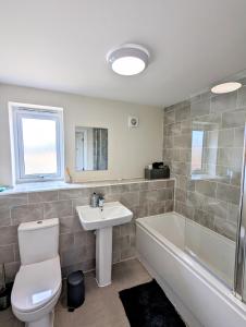 een badkamer met een toilet, een wastafel en een bad bij Apollo Avenue Apartment in Stony Stratford