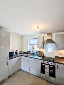 a large kitchen with white appliances and a window at Apollo Avenue Apartment in Stony Stratford